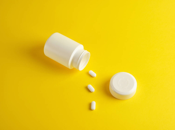 薬や楕円形の丸薬のための開いた白いプラスチック瓶  - 写真・画像