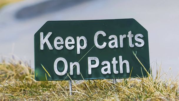 Marco panorámico Cierre de un letrero que dice Keep Carts On Path junto a un camino pavimentado
 - Foto, Imagen