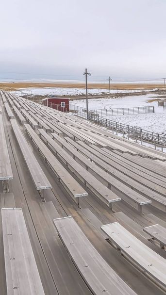 Vertical frame Bleachers overlooking a sports field covered with snow in winter - Photo, Image