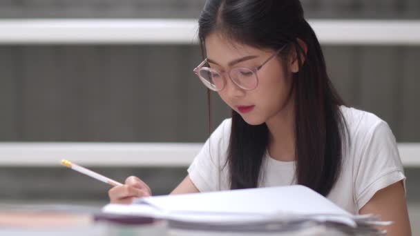 Étudiantes asiatiques lisant des livres à la bibliothèque de l'université. Jeune fille de premier cycle faire des devoirs, lire le manuel, étudier dur pour la connaissance et l'éducation sur le bureau de conférence sur le campus de l'université. Mouvement lent
. - Séquence, vidéo