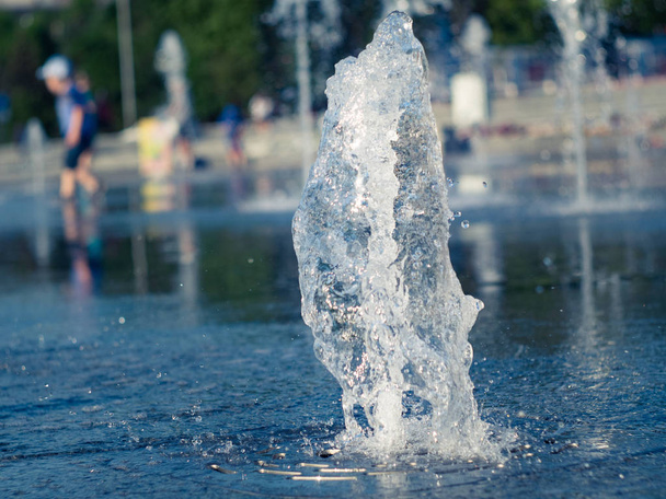 Сухий фонтан на головній площі міста, вид крупним планом. Діти ходять голими ногами між водними потоками. Літній пейзаж. Вибірковий м'який фокус. Розмитий фон
. - Фото, зображення