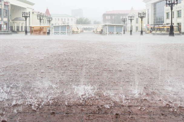 Сильний дощ у місті. Міська площа. Крупним планом тротуар з прямокутними плитками під водою
 - Фото, зображення