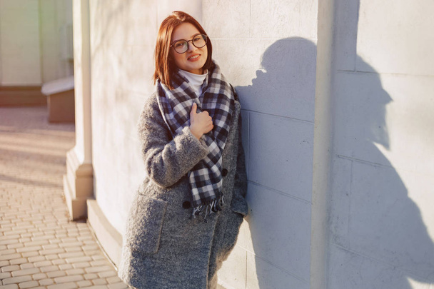 Atractiva joven con gafas en un abrigo caminando en un día soleado
 - Foto, imagen