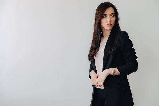 Young attractive emotional girl in business-style clothes on a plain white background in an office or audience - Foto, imagen