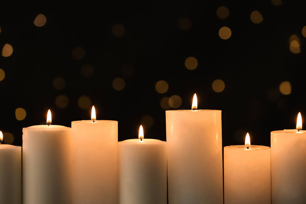 Burning candles on black background with blurred lights - Photo, image