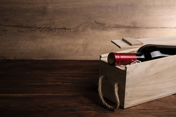 Open wooden crate with bottle of wine on table, space for text - Foto, Imagem