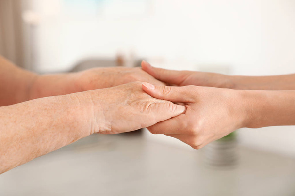 People holding hands together on blurred background, closeup. Help and elderly care concept - Photo, Image