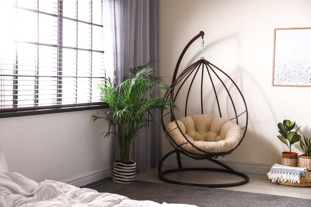 Comfortable swing chair with pillow in bedroom interior - 写真・画像