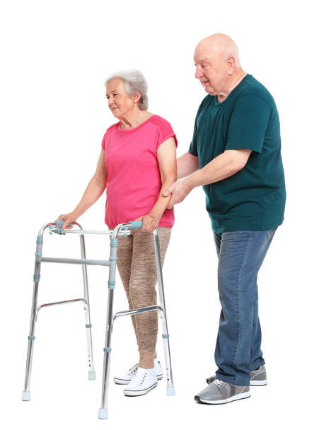 Homme âgé aidant sa femme avec cadre de marche sur fond blanc
 - Photo, image