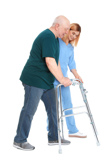 Caretaker helping elderly man with walking frame on white background - Foto, Imagen