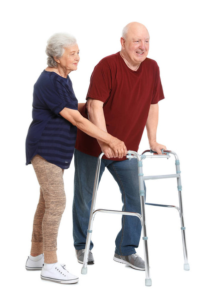 Elderly woman helping her husband with walking frame on white background - Foto, Imagen
