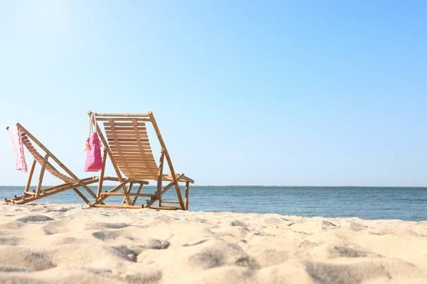 Empty wooden sunbeds and beach accessories on sandy shore - Foto, Imagen