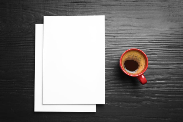 Blank paper sheets for brochure and cup of coffee on black wooden background, flat lay. Mock up - Valokuva, kuva