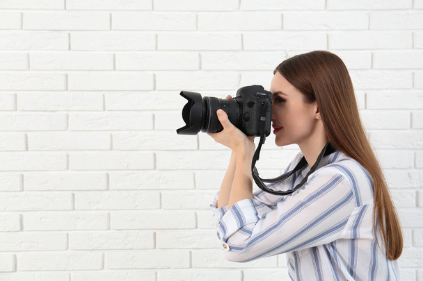Professional photographer taking picture near white brick wall - Photo, Image
