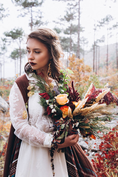 Wedding floristry in a yellow autumn meadow in the hands of a girl dressed in the style of boho. - 写真・画像