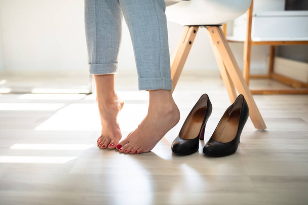 Close-up Of A Woman's Leg Near High Heels On Hardwood Floor - Zdjęcie, obraz