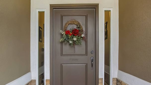Cornice panoramica Ghirlanda floreale appesa alla porta d'ingresso grigia di una casa con piaceri
 - Foto, immagini
