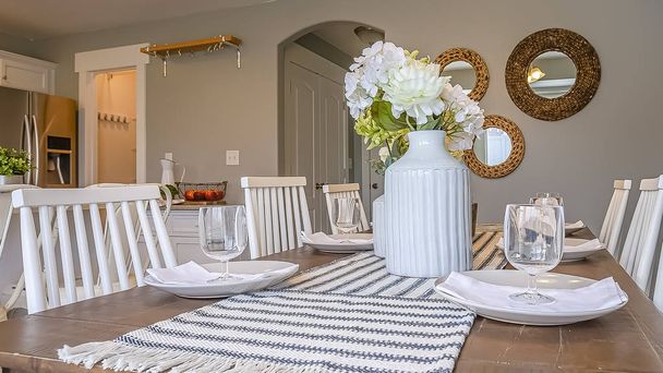 Panoramatický rám interiér jídelny s hnědou dřevěnou stolovou výzdobou a bílými dřevěnými židlemi - Fotografie, Obrázek