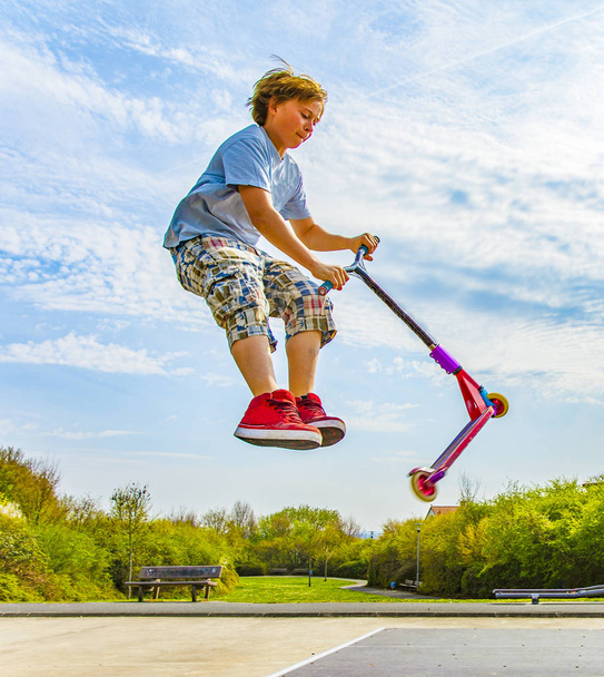 Мальчик прыгает на скутере через хребет в скейт-парке
 - Фото, изображение