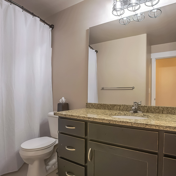 Туалет и инструмент Square Vanity прижались к белой стене хорошо освещенной ванной комнаты
 - Фото, изображение