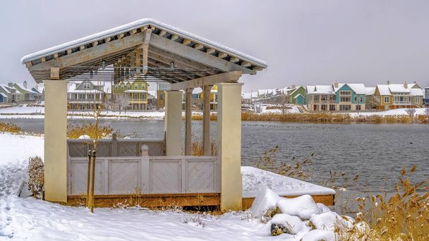 Panorama-Pavillon am schneebedeckten Ufer eines Sees an einem bewölkten Wintertag - Foto, Bild