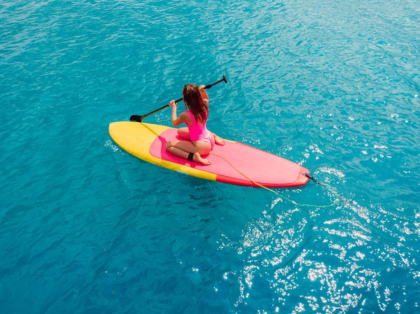 Vista aérea da mulher em stand up paddle board no oceano
. - Foto, Imagem
