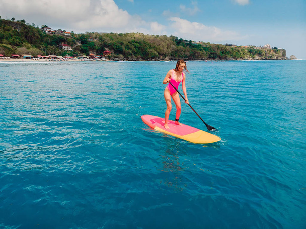 Mujer en stand up paddle board en el mar azul. Disparo aéreo
 - Foto, imagen
