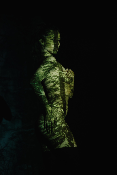 приваблива роздягнена молода жінка з тінями на тілі, стоячи на чорному
  - Фото, зображення