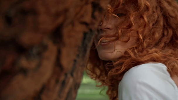 parkta gülümseyen mutlu kızıl saçlı kadının seçici odak  - Video, Çekim