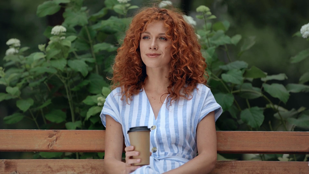 wesoły ruda dziewczyna picie kawy do iść w Park  - Materiał filmowy, wideo