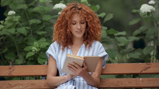 parkta kitap okuyan mutlu kızıl saçlı kız - Video, Çekim