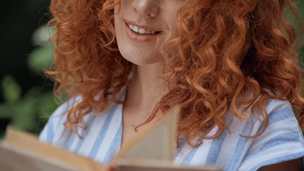 Focus pull of cheerful curly girl reading book  - Footage, Video