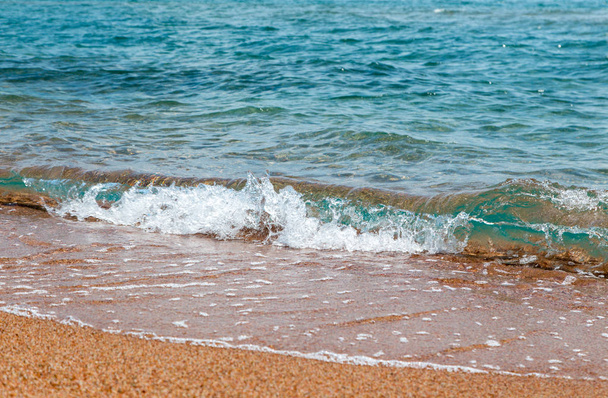αμμώδη παραλία και το γαλάζιο κύμα της θάλασσας. Όμορφο φυσικό φόντο. - Φωτογραφία, εικόνα