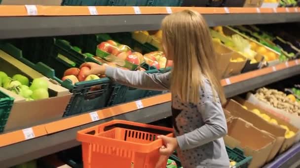 little girl at the grocery store buys apples. - Video, Çekim