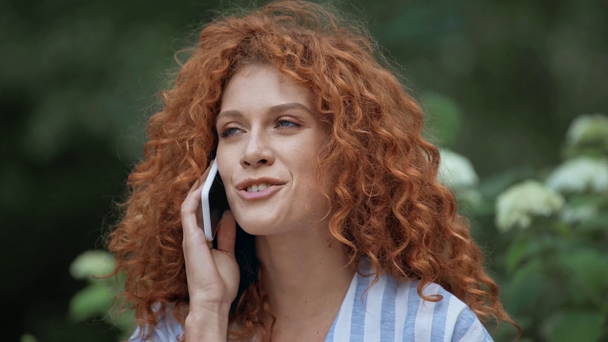公園でスマートフォンで話す幸せな赤毛の女性  - 映像、動画