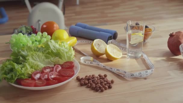 koncepció megfelelő táplálkozás, az asztalra súlyzók mérőszalag zöldség gyümölcsök és diófélék - Felvétel, videó
