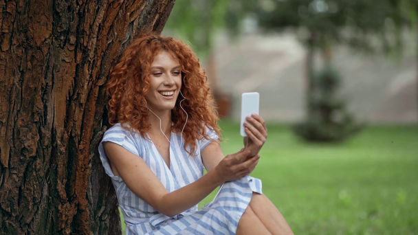 szczęśliwy rudowłosy dziewczyna mający wideo rozmowa na smartphone  - Materiał filmowy, wideo