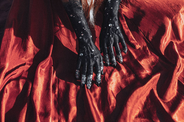 close up of woman hands painted black on red fabric.  - Photo, Image