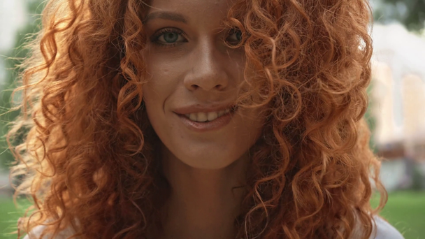 Focus pull of cheerful curly woman in park  - Materiał filmowy, wideo