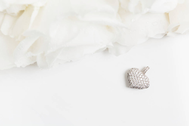 White golden pendant with diamonds and bouquet of white roses with copy space. Flat lay. Top view. Mockup - Fotoğraf, Görsel