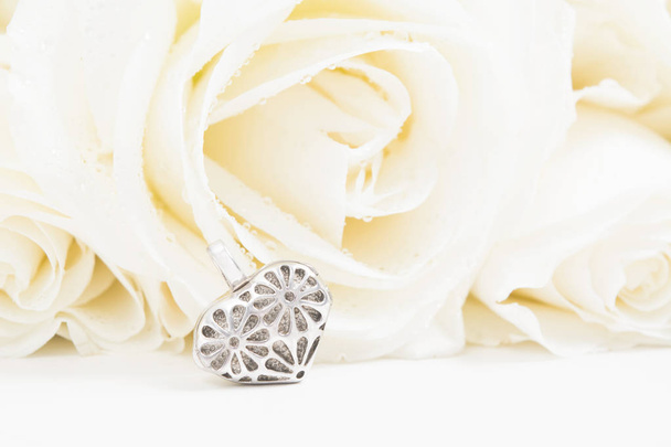 Beautiful golden heart shape jewelry with white roses on background with copy space. Valentine's day gift. Symbol of love. Selective focus - Fotoğraf, Görsel