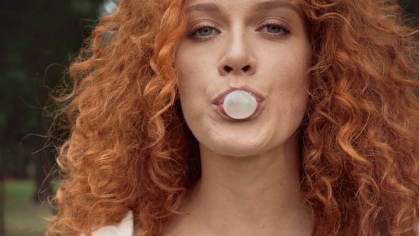 バブルガムを吹く赤毛の女の子のクローズアップ  - 映像、動画