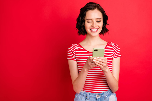 Portrait of her she nice attractive pretty lovely cheerful cheery addicted wavy-haired teen girl spending free time using wi-fi isolated over bright vivid shine red background - Zdjęcie, obraz