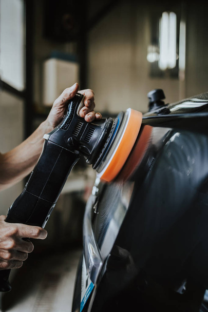 Car detailing - Hands with orbital polisher in auto repair shop. Selective focus. - Fotoğraf, Görsel