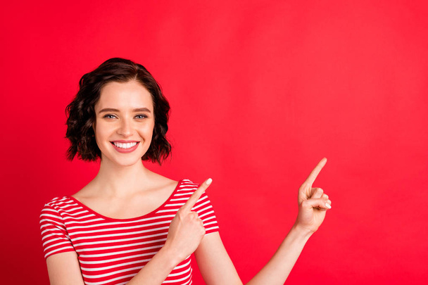 Close-up portrait of her she nice attractive lovely pretty charming cheerful cheery glad content wavy-haired lady pointing two forefingers aside ad advert isolated on bright vivid shine red background - Valokuva, kuva
