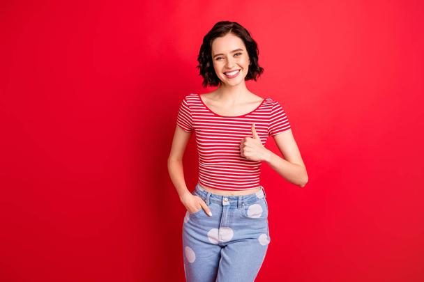 Photo of girl thumbing up in order to advise you some goods being recommended to buy while isolated with red background - Zdjęcie, obraz