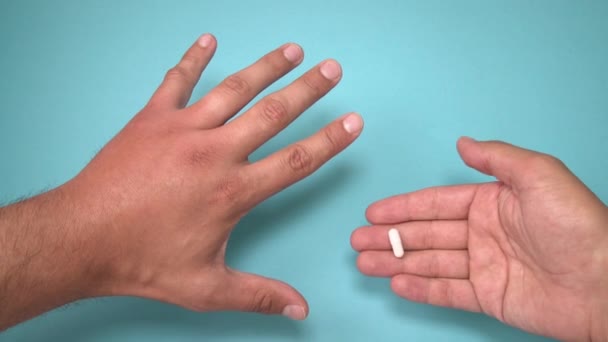 男性の手は蜂に刺され、その隣に腫れのための薬。手の腫れ、炎症、発赤は感染の徴候である。青い背景に昆虫の咬傷と錠剤 - 映像、動画