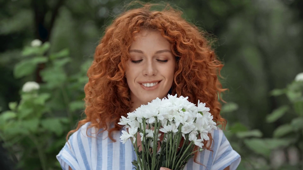 επιλεκτική εστίαση του ευτυχισμένο κορίτσι κρατώντας λουλούδια στο πάρκο  - Πλάνα, βίντεο