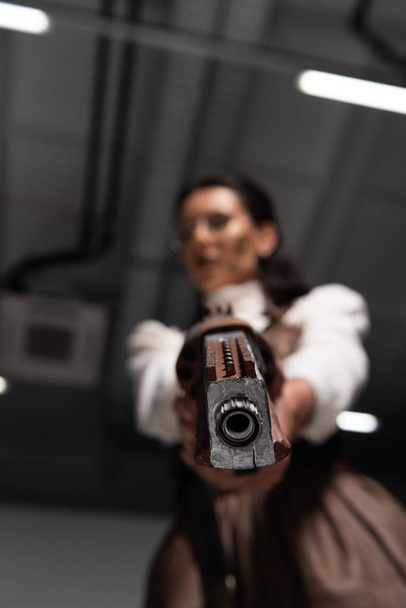 selective focus of confident steampunk woman aiming with pistol at camera - Foto, Bild