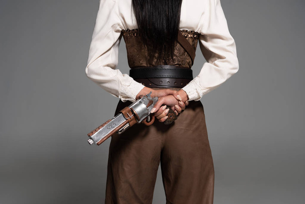 cropped view of steampunk woman holding vintage pistol on grey - Zdjęcie, obraz